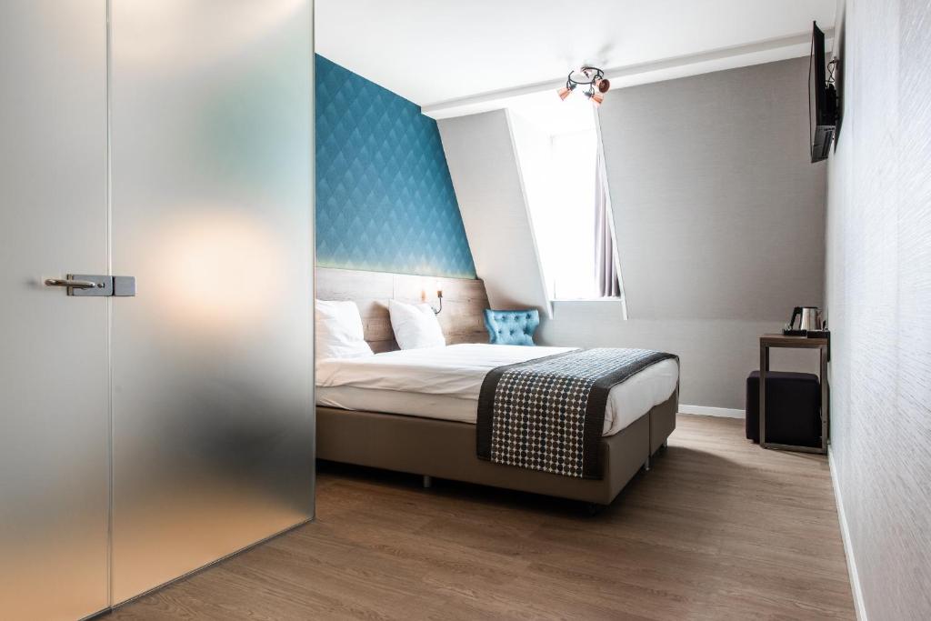 1 dormitorio con 1 cama con pared azul en Melrose Hotel, en Ámsterdam