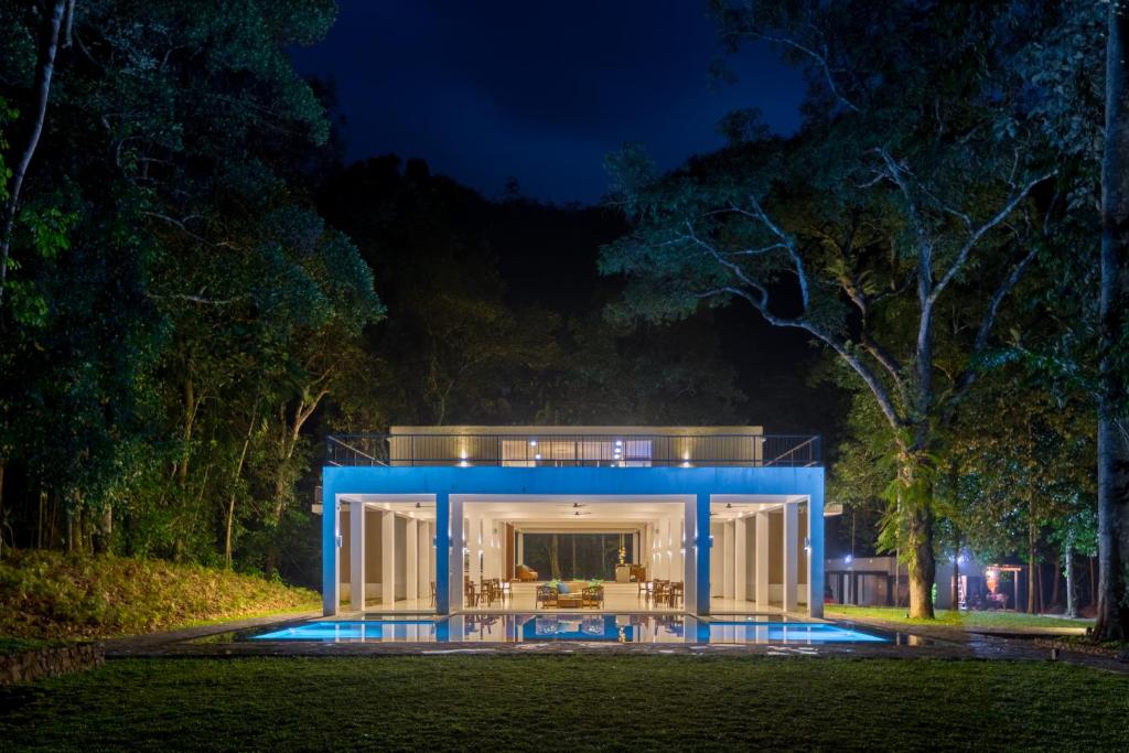 a house with a blue facade at night at Palmstone Retreat in Kitulgala