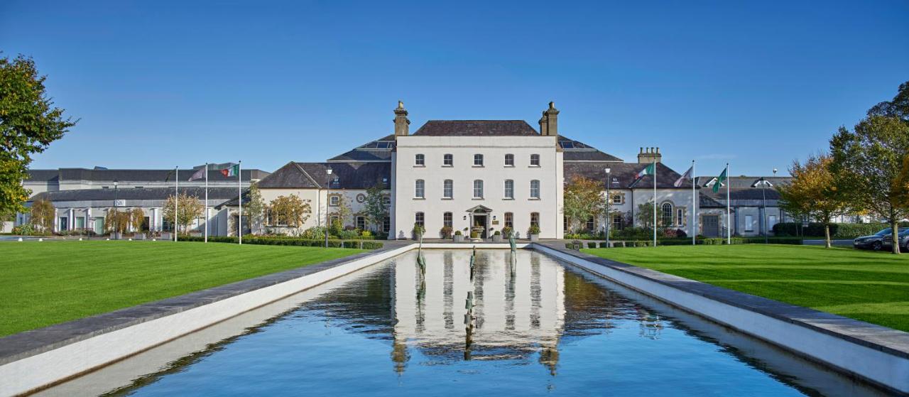 Large white building with a reflecting pool in front under a clear blue sky.