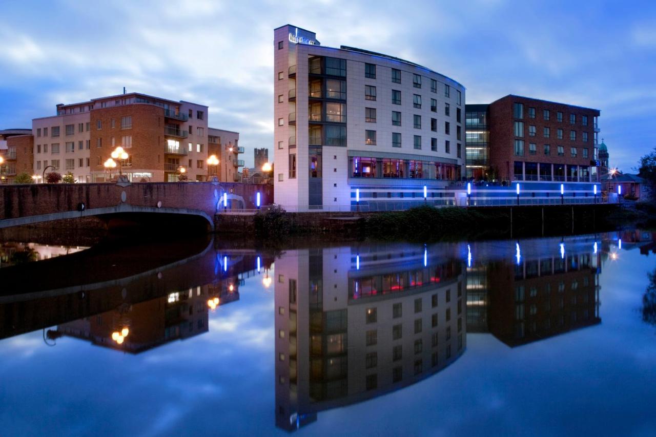 Modern hotel and its reflection on water at twilight.