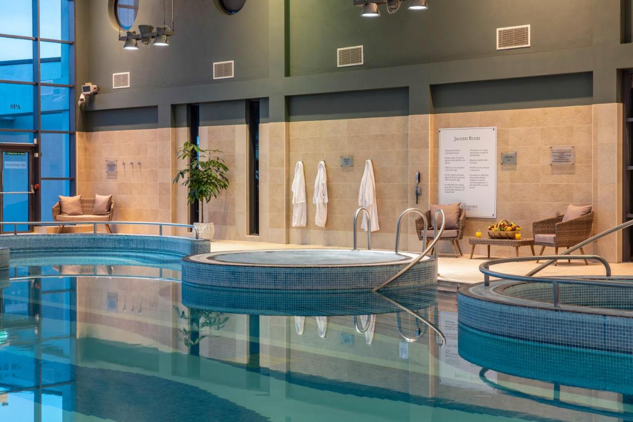 Indoor swimming pool and jacuzzi area with lounge chairs and robes.