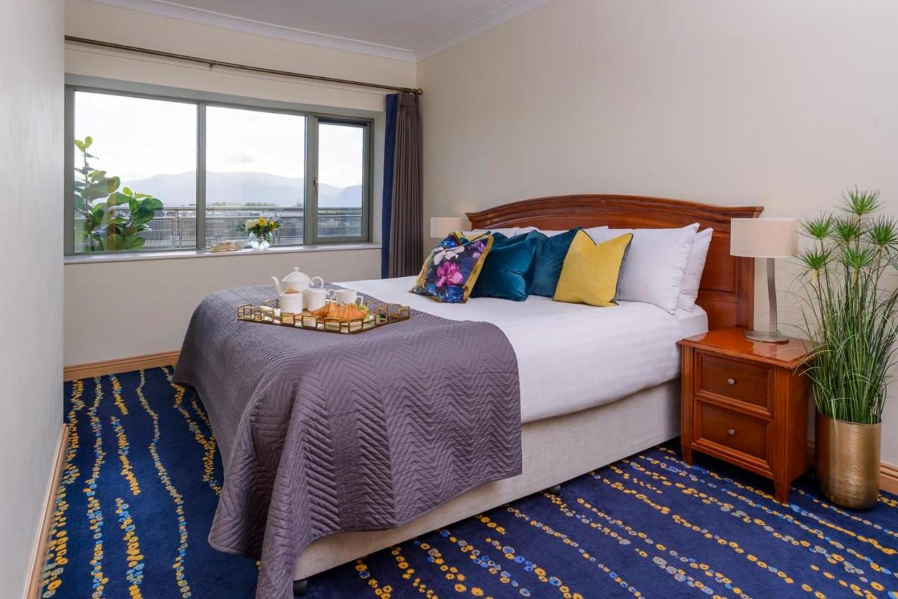 A cozy bedroom with a neatly made bed, colorful pillows, and a tray with breakfast items.