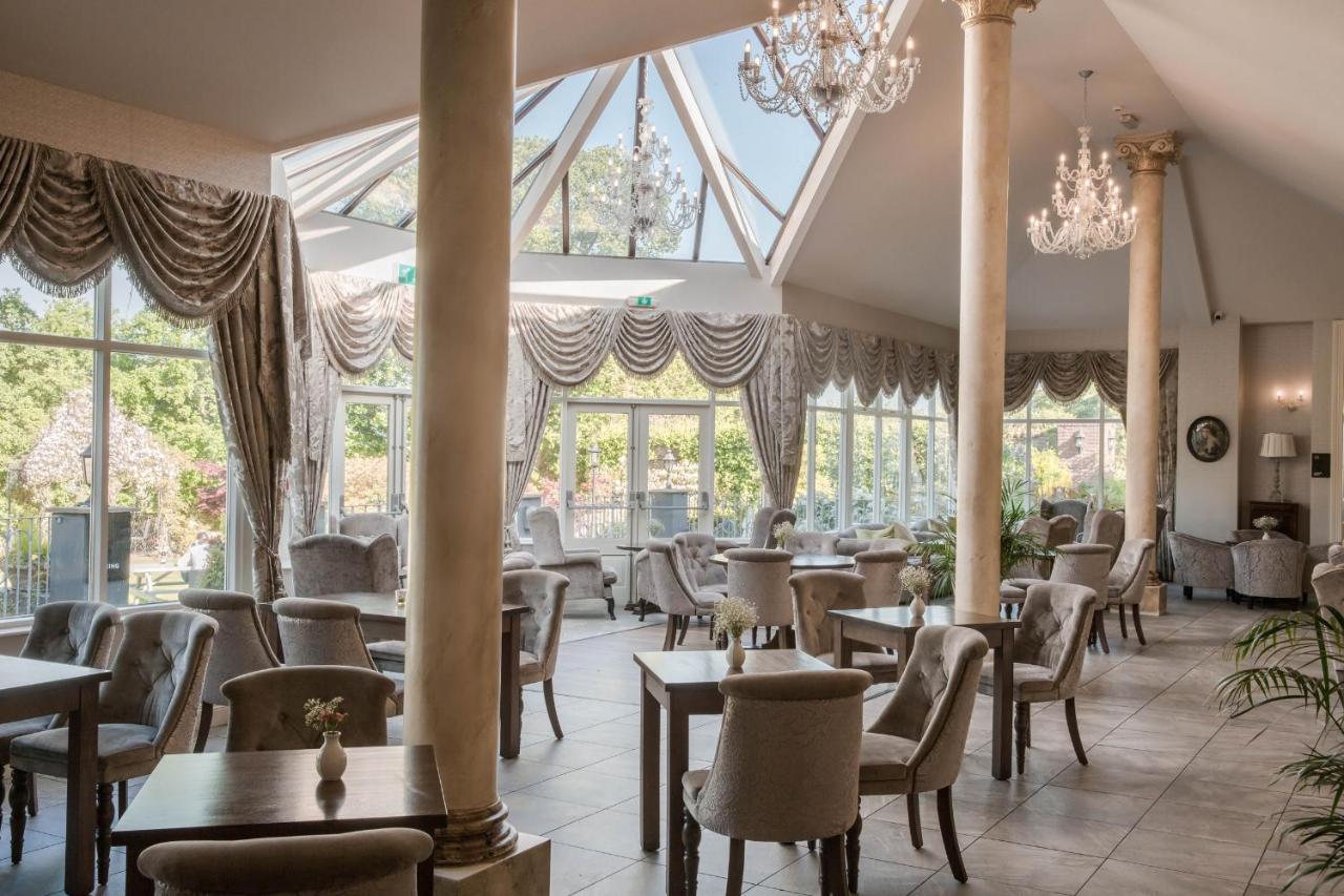 Elegant dining area with tall windows, chandeliers, and plush seating.