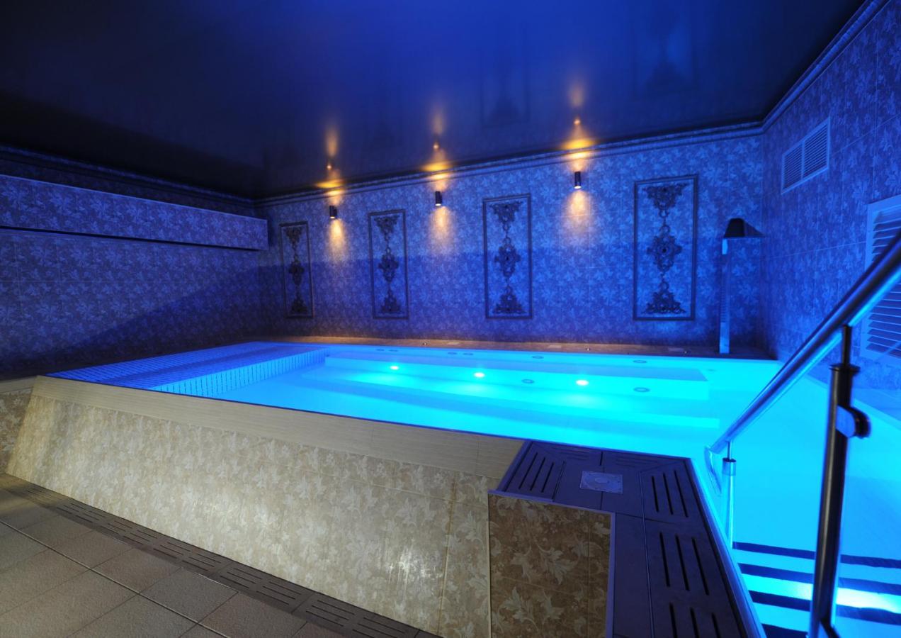 Indoor spa pool with blue lighting and decorative walls.