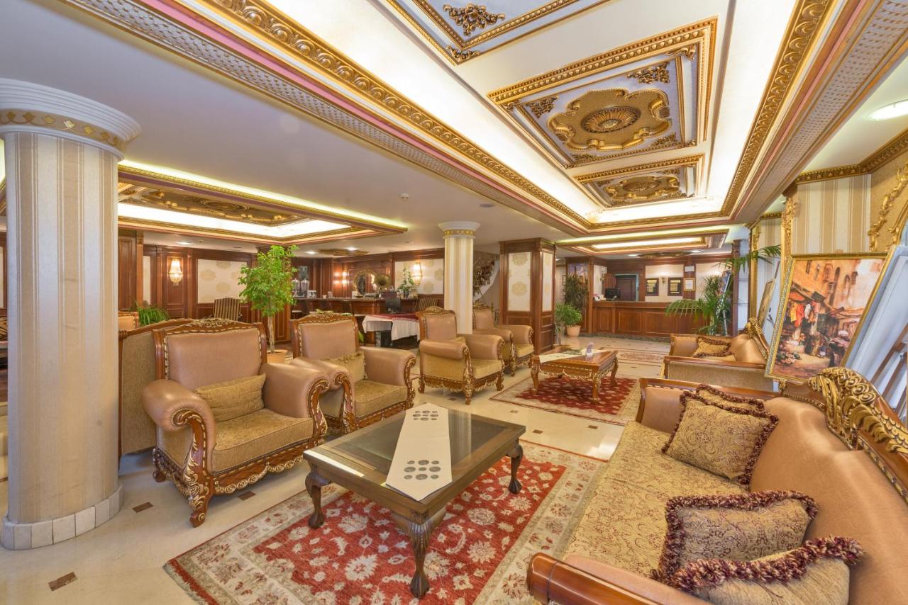 Luxurious hotel lobby with ornate ceiling, elegant seating, and plush rugs.
