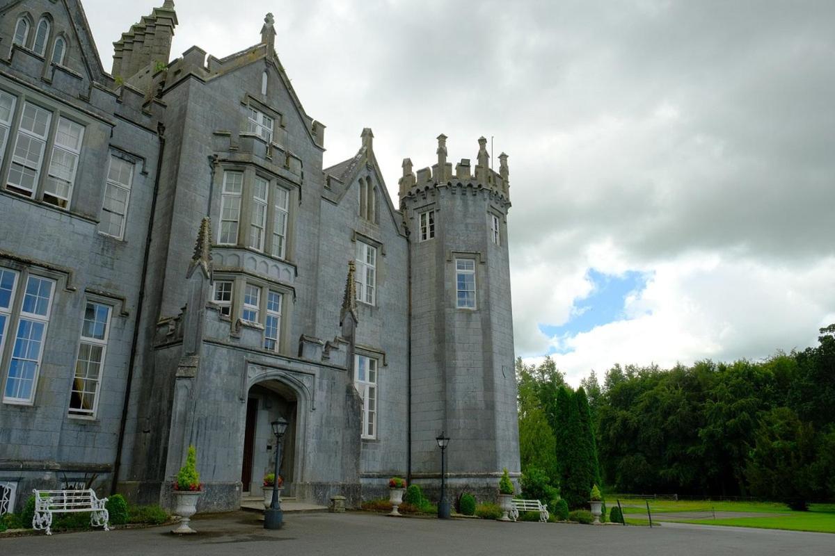 A historic stone mansion with a turret against a cloudy sky.