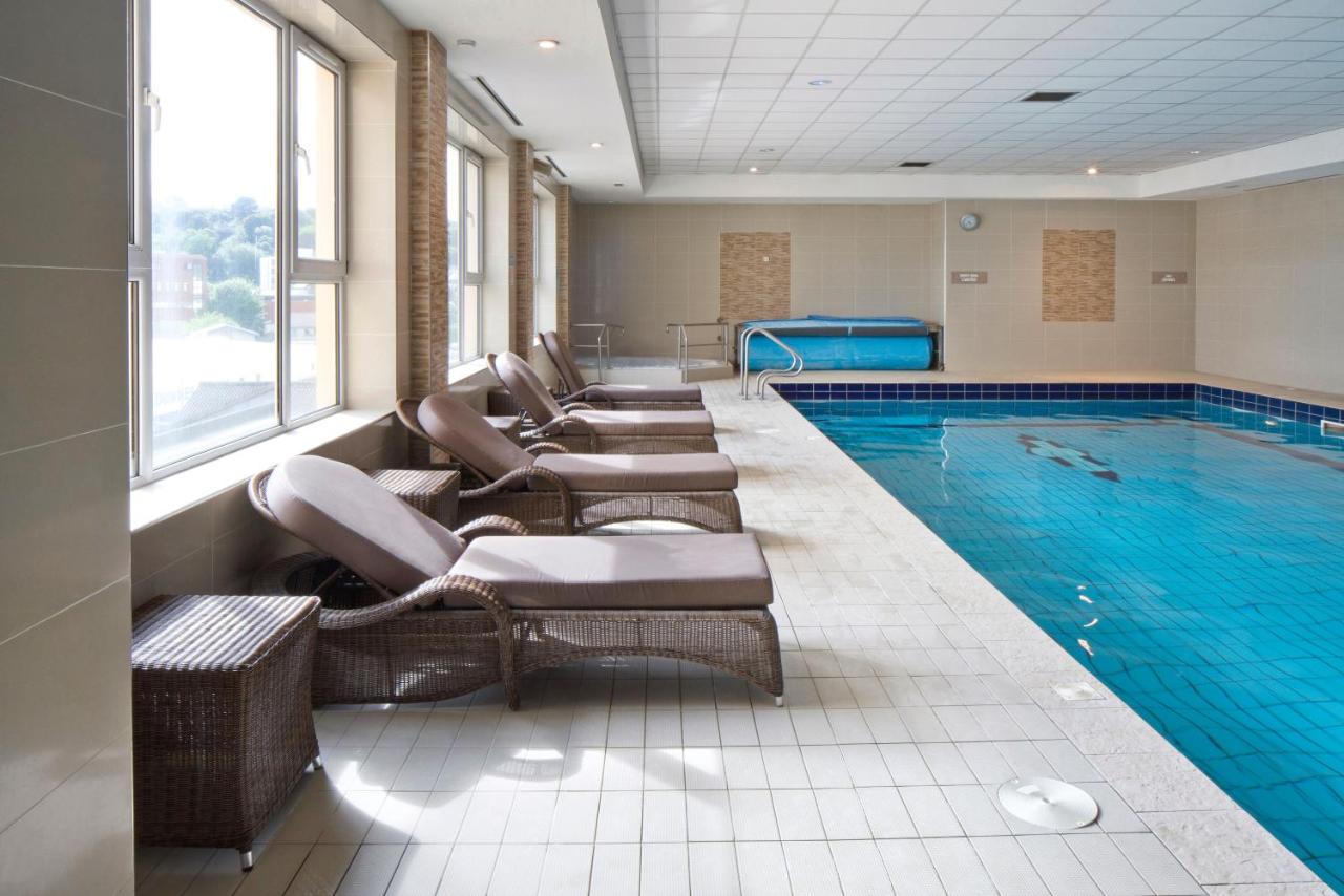 Indoor swimming pool with lounge chairs along the side.