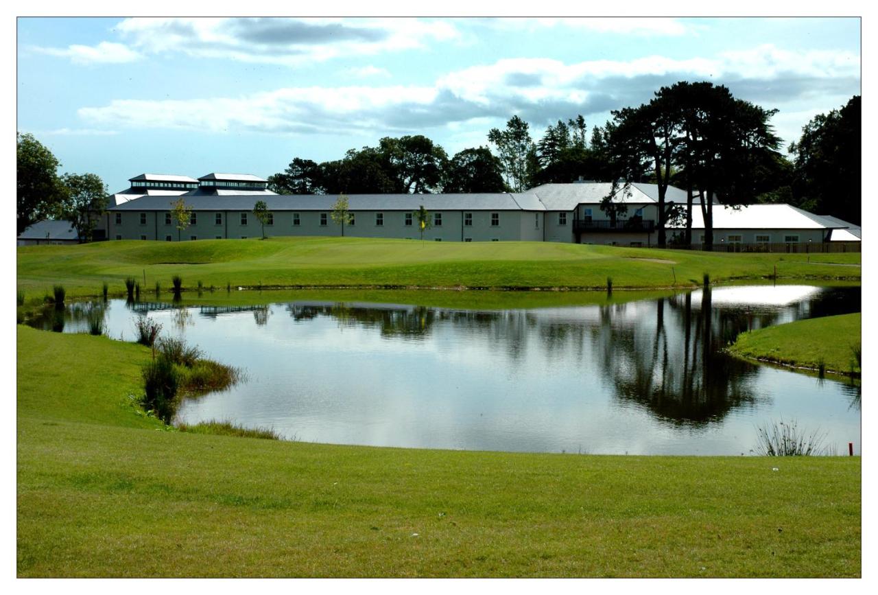 Building with green surroundings and a pond reflecting the scenery.