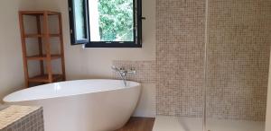 baño con bañera blanca y ventana en Clairseine en Tournedos-sur-Seine