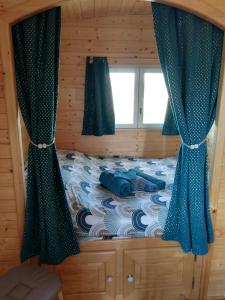 - une chambre avec un lit doté de rideaux bleus et d'une fenêtre dans l'établissement Roulot'So Zen, à Beslon