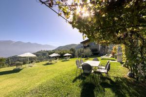 a table and chairs in a yard with mountains in the background at Mos Country House in Tremosine Sul Garda